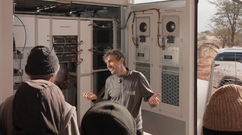 Researchers and technicians discussing the green hydrogen and wastewater treatment system inside a containerised facility at Kalahari Anib Lodge, Namibia.