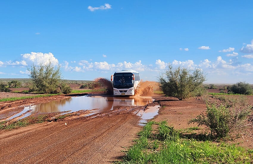 Gondwana Academy bus driving thourgh puddle on gravel road, Namibia