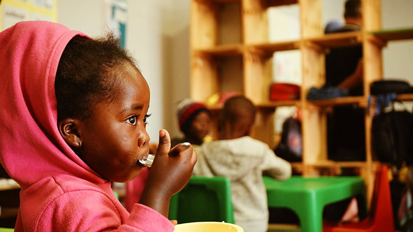 Little Namibian girl eating with spoon