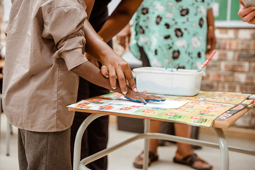 Namibian child making a blue handprint