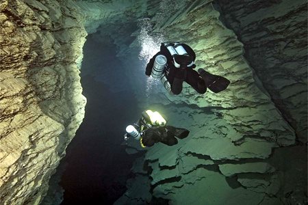Divers exploring the lake in a cave, Namibia