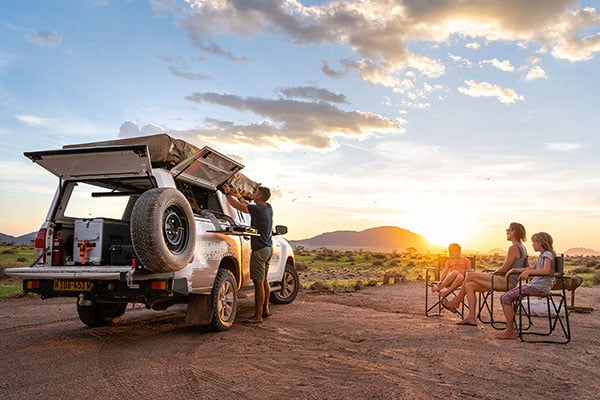 Family with camping vehicle at sunset, Namibia