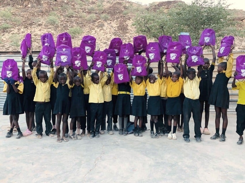 School kids lifting schoolbags in the Kunene Region Schools after recieving donations through Gondwana Care Trust Namibia