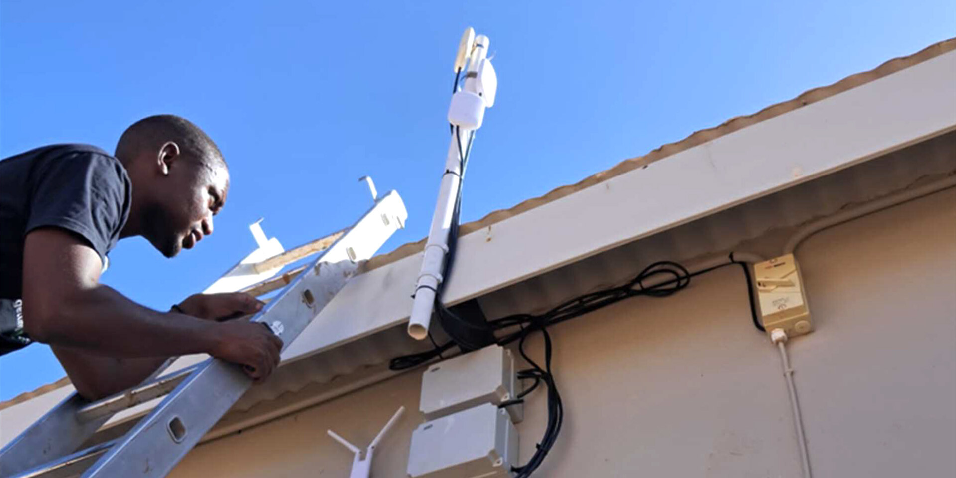 Namibian man installing wifi on a roof