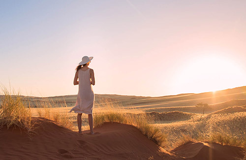 Woman watching sunset in the Namib Desert, Namibia