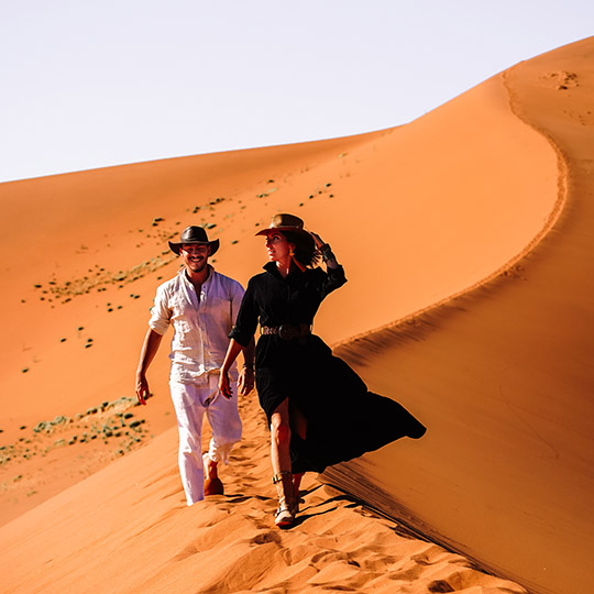Couple walking dwon a sand dune in Namibia, laughingValentines gallery web